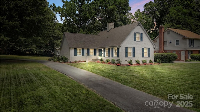 4201 Tyndale Ave, Charlotte, NC 28210 - new england style home with a front yard, a chimney, driveway, brick siding, and a shingled roof