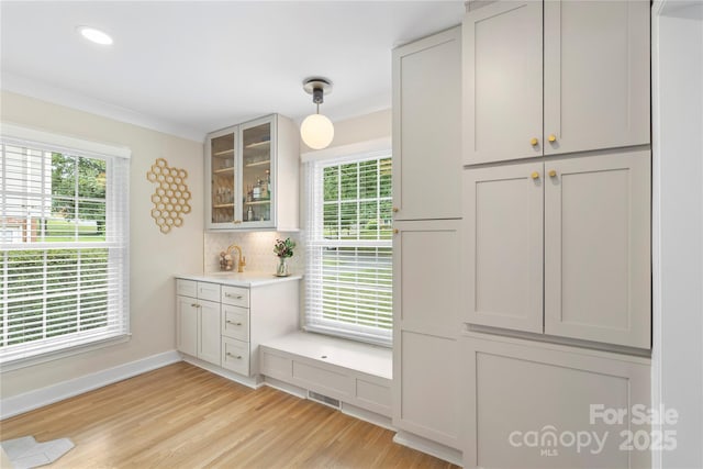 4201 Tyndale Ave, Charlotte, NC 28210 - kitchen featuring healthy amount of natural light, glass insert cabinets, light countertops, light wood finished floors, and ornamental molding