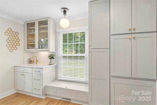 4201 Tyndale Ave, Charlotte, NC 28210 - kitchen featuring decorative backsplash, glass insert cabinets, light wood-style flooring, light countertops, and decorative light fixtures