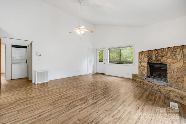 263 Shannons Walk, Lake Lure, NC 28746 - unfurnished living room featuring estacked washer and dryer, high vaulted ceiling, a ceiling fan, wood finished floors, and a stone fireplace