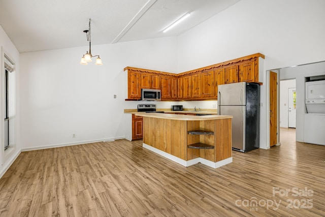 263 Shannons Walk, Lake Lure, NC 28746 - kitchen with appliances with stainless steel finishes, high vaulted ceiling, stacked washing machine and dryer, light countertops, and light wood-type flooring
