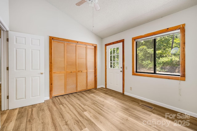 263 Shannons Walk, Lake Lure, NC 28746 - unfurnished bedroom with light wood-style flooring, multiple windows, vaulted ceiling, a closet, and a textured ceiling