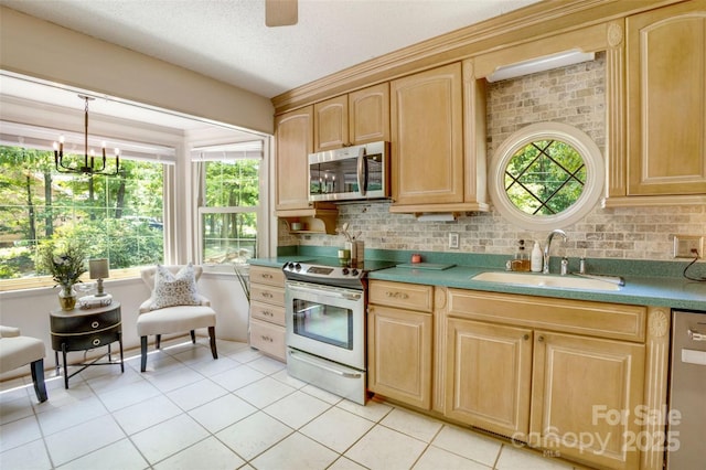 924 Holly Rd, Rock Hill, SC 29730 - kitchen with appliances with stainless steel finishes, light brown cabinetry, a chandelier, light tile patterned flooring, and decorative backsplash