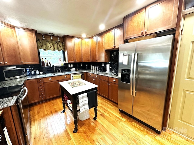 25 Norman Rd, Fletcher, NC 28732 - kitchen with appliances with stainless steel finishes, light wood-type flooring, tasteful backsplash, light stone counters, and brown cabinetry