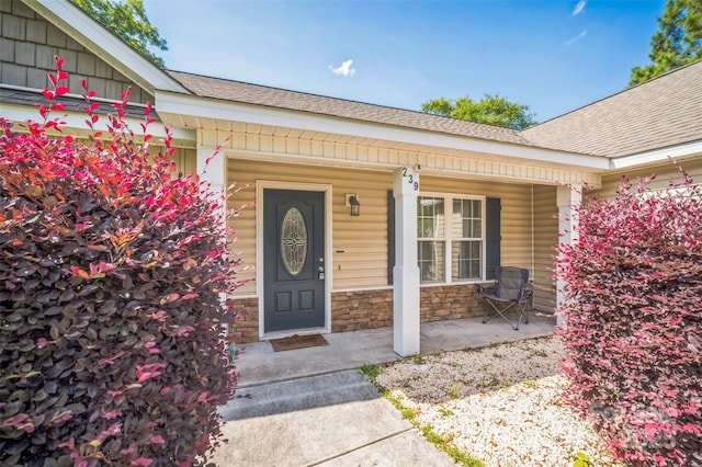 239 Shellbank Dr, Sneads Ferry, NC 28460 - view of exterior entry with a porch, a shingled roof, and stone siding