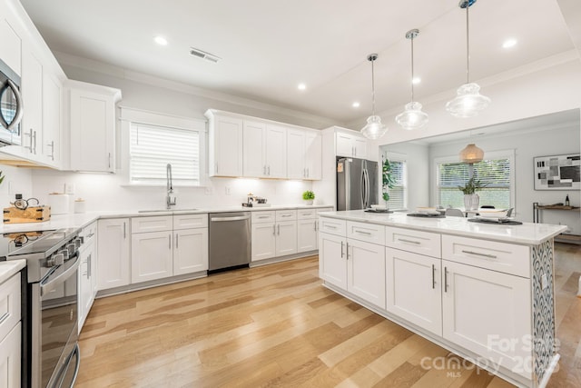 5305 Tarrywood Ln, Charlotte, NC 28205 - kitchen featuring appliances with stainless steel finishes, light wood finished floors, ornamental molding, light countertops, and white cabinets
