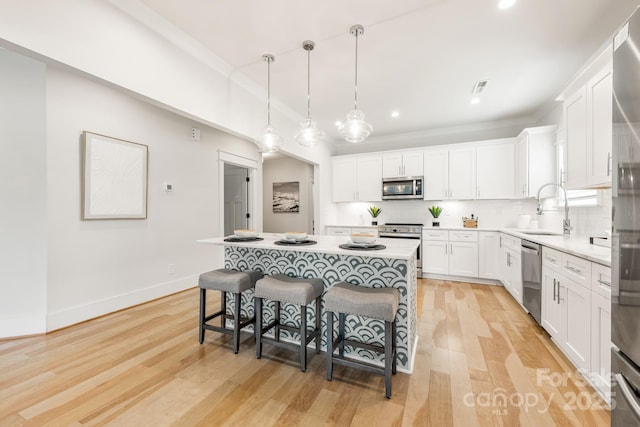 5305 Tarrywood Ln, Charlotte, NC 28205 - kitchen featuring appliances with stainless steel finishes, a breakfast bar area, light wood-style flooring, white cabinetry, and recessed lighting