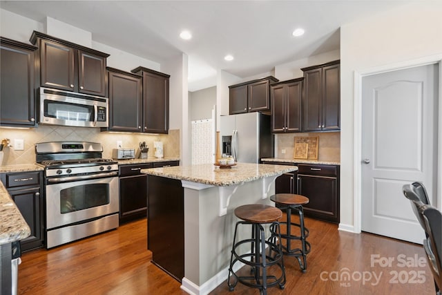 6029 Piscataway Ct, Rock Hill, SC 29732 - kitchen featuring appliances with stainless steel finishes, dark brown cabinets, dark wood finished floors, light stone counters, and recessed lighting