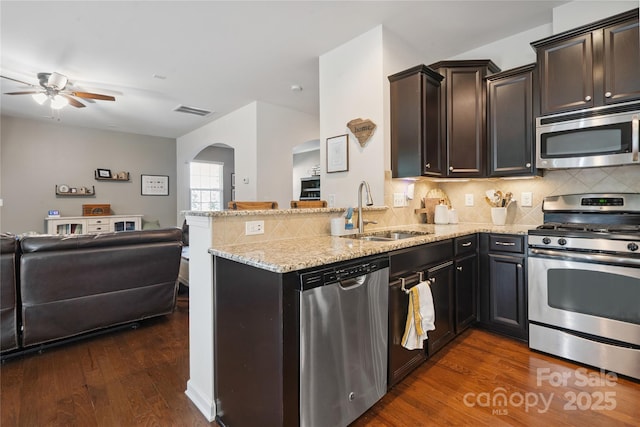 6029 Piscataway Ct, Rock Hill, SC 29732 - kitchen featuring stainless steel appliances, open floor plan, arched walkways, ceiling fan, and light stone countertops