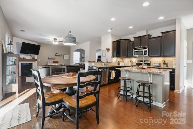 6029 Piscataway Ct, Rock Hill, SC 29732 - dining area featuring ceiling fan, dark wood finished floors, a fireplace, recessed lighting, and arched walkways