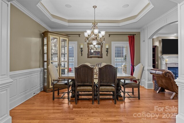 3211 Keady Mill Loop, Kannapolis, NC 28081 - dining room featuring a raised ceiling, arched walkways, light wood finished floors, a chandelier, and a glass covered fireplace