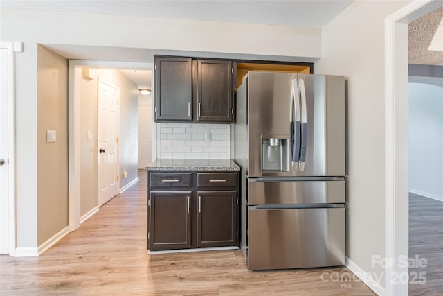 8909 Raven Park Dr, Charlotte, NC 28216 - kitchen with stainless steel fridge, backsplash, dark brown cabinets, light wood-type flooring, and light stone countertops