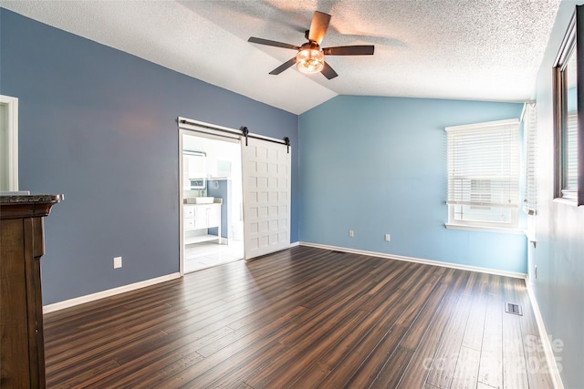 8909 Raven Park Dr, Charlotte, NC 28216 - empty room with a barn door, a ceiling fan, lofted ceiling, wood finished floors, and a textured ceiling