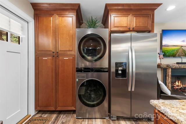 8333 Catawba Cove Dr, Belmont, NC 28012 - kitchen featuring stainless steel fridge, stacked washer and clothes dryer, brown cabinetry, light stone counters, and wood finished floors