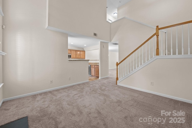 348 Tidmarsh Ct NW, Concord, NC 28027 - unfurnished living room with light carpet, stairway, and a high ceiling