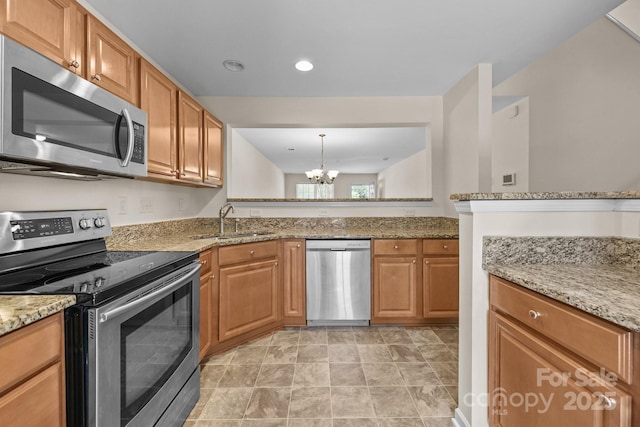 348 Tidmarsh Ct NW, Concord, NC 28027 - kitchen featuring appliances with stainless steel finishes, a chandelier, light stone countertops, brown cabinets, and recessed lighting
