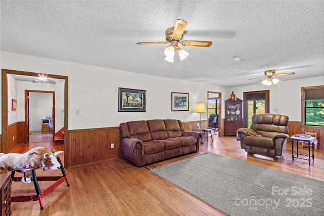 144 J And W Rd, Olin, NC 28660 - living area with a wainscoted wall, light wood finished floors, a ceiling fan, a textured ceiling, and wooden walls