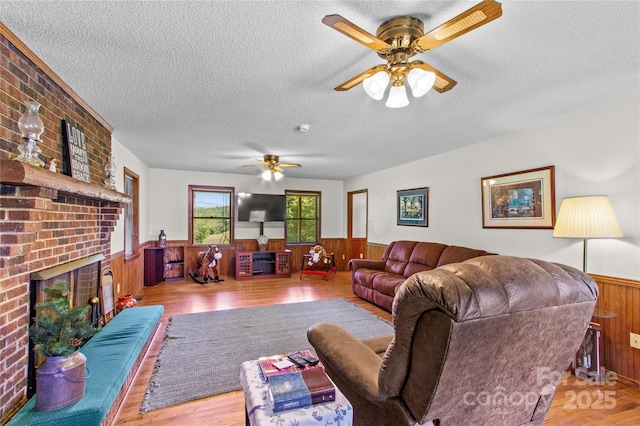 144 J And W Rd, Olin, NC 28660 - living room with a wainscoted wall, wooden walls, ceiling fan, a textured ceiling, and a brick fireplace
