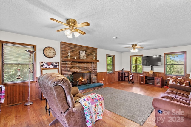 144 J And W Rd, Olin, NC 28660 - living area featuring a ceiling fan, wainscoting, a textured ceiling, a fireplace, and wood finished floors