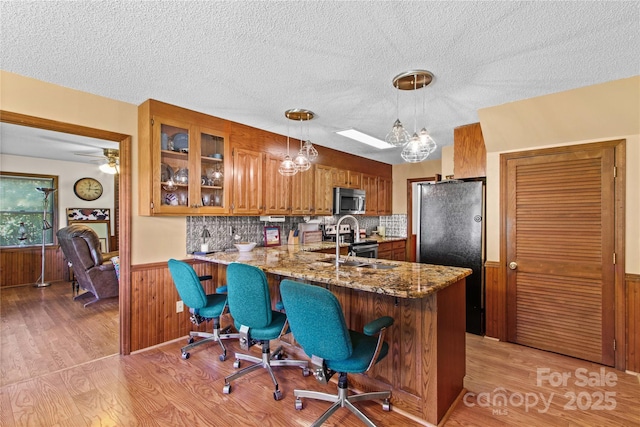 144 J And W Rd, Olin, NC 28660 - kitchen featuring appliances with stainless steel finishes, brown cabinets, a peninsula, wainscoting, and light stone counters