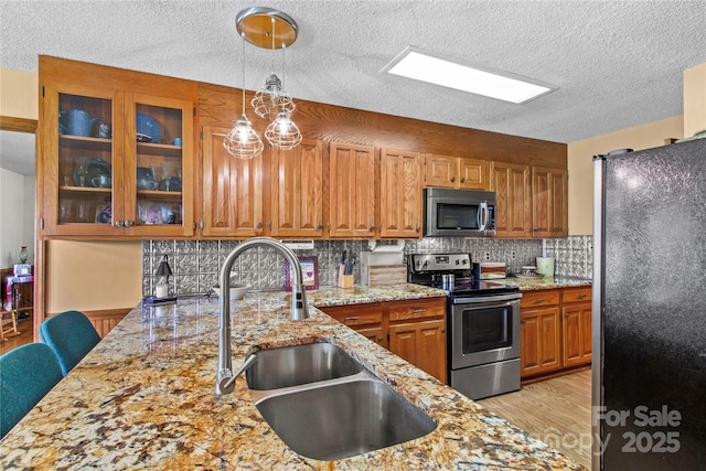 144 J And W Rd, Olin, NC 28660 - kitchen featuring appliances with stainless steel finishes, light stone counters, light wood-type flooring, decorative backsplash, and pendant lighting