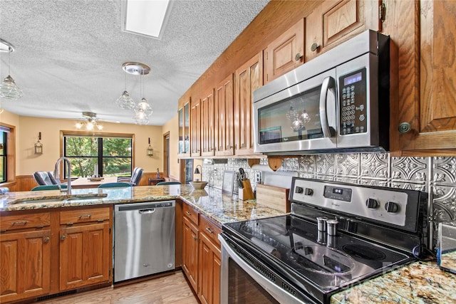 144 J And W Rd, Olin, NC 28660 - kitchen with appliances with stainless steel finishes, brown cabinets, ceiling fan, light stone countertops, and a peninsula