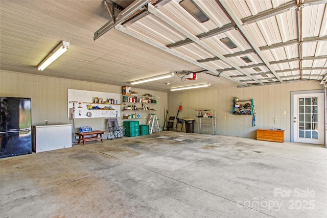 144 J And W Rd, Olin, NC 28660 - garage featuring freestanding refrigerator, a garage door opener, and wooden walls