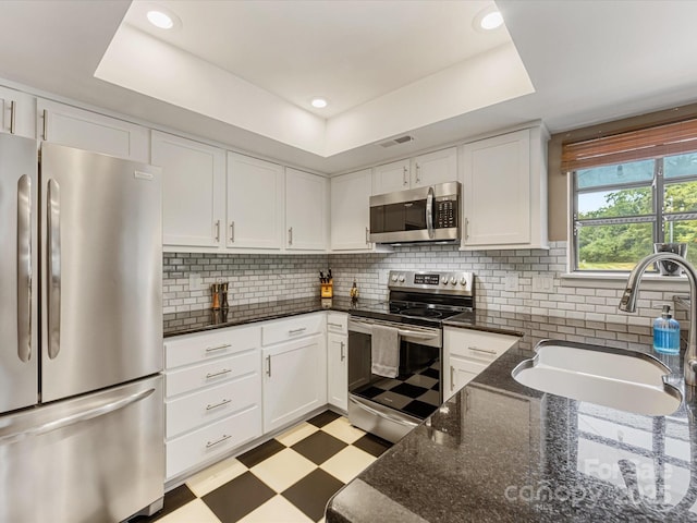 9237 N Vicksburg Park Ct, Charlotte, NC 28210 - kitchen with appliances with stainless steel finishes, light flooring, a raised ceiling, white cabinets, and recessed lighting