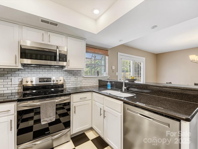 9237 N Vicksburg Park Ct, Charlotte, NC 28210 - kitchen with stainless steel appliances, white cabinets, decorative backsplash, and dark stone counters