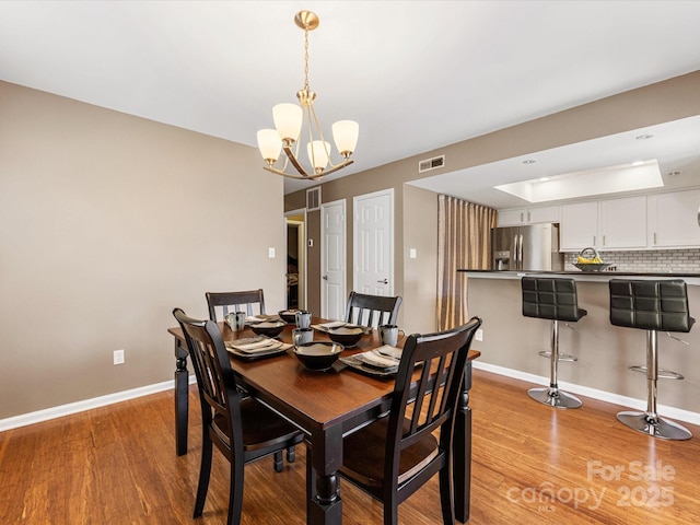 9237 N Vicksburg Park Ct, Charlotte, NC 28210 - dining room featuring light wood finished floors, a raised ceiling, and a chandelier