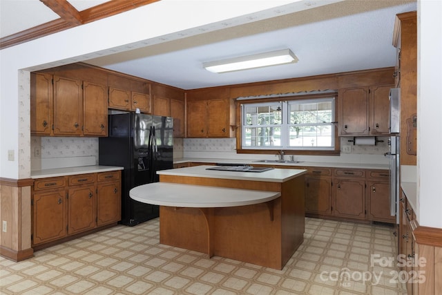 621 Big Lick Rd, Oakboro, NC 28129 - kitchen featuring black appliances, light flooring, brown cabinets, light countertops, and a center island