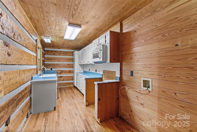 179 J And W Rd, Olin, NC 28660 - kitchen featuring white microwave, wooden ceiling, light wood-type flooring, white cabinetry, and wooden walls
