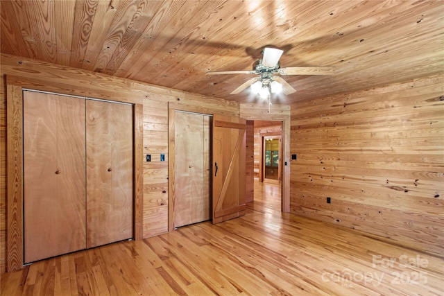 179 J And W Rd, Olin, NC 28660 - unfurnished bedroom with wood walls, two closets, wood ceiling, light wood finished floors, and ceiling fan