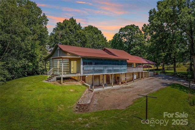 179 J And W Rd, Olin, NC 28660 - back of house at dusk with dirt driveway, a metal roof, a lawn, and a wooden deck