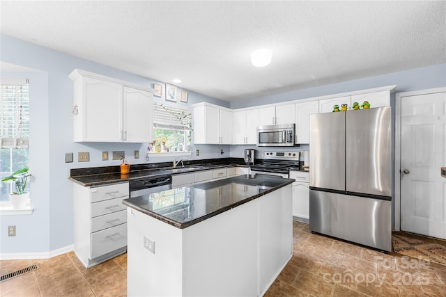 7410 Derby Meadows Ct, Charlotte, NC 28216 - kitchen featuring stainless steel appliances, white cabinets, a textured ceiling, light tile patterned floors, and a center island
