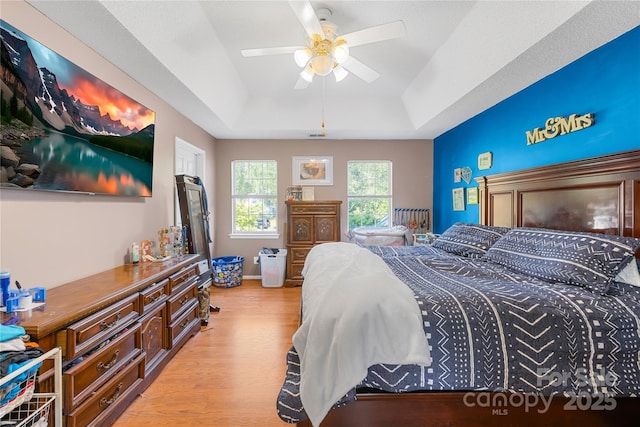 7410 Derby Meadows Ct, Charlotte, NC 28216 - bedroom with a tray ceiling, light wood finished floors, and a ceiling fan