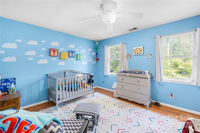 7410 Derby Meadows Ct, Charlotte, NC 28216 - bedroom featuring wood finished floors, ceiling fan, a crib, and a textured ceiling