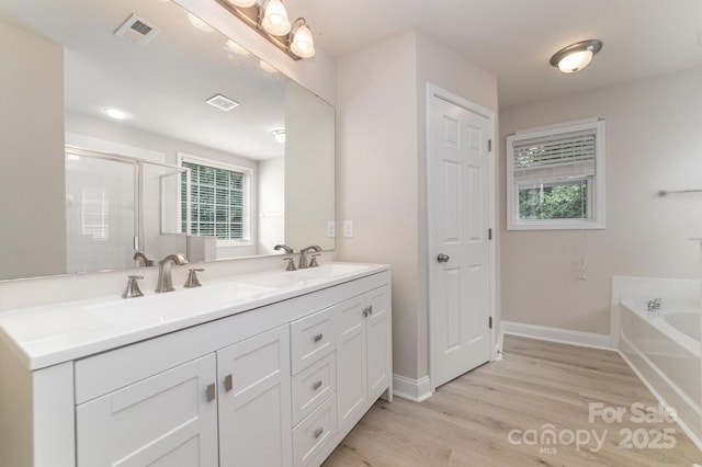 9836 Coatbridge Dr NW, Charlotte, NC 28269 - bathroom featuring double vanity, wood finished floors, a bath, and a shower with door