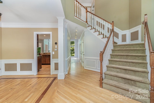 6225 Ash Cove Ln, Charlotte, NC 28269 - foyer entrance with light wood finished floors, stairs, crown molding, a decorative wall, and a wainscoted wall