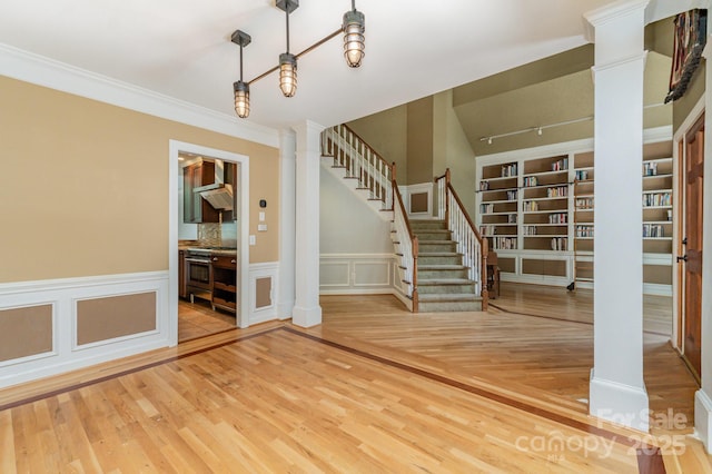 6225 Ash Cove Ln, Charlotte, NC 28269 - entrance foyer featuring ornate columns, wood finished floors, stairway, wainscoting, and a decorative wall