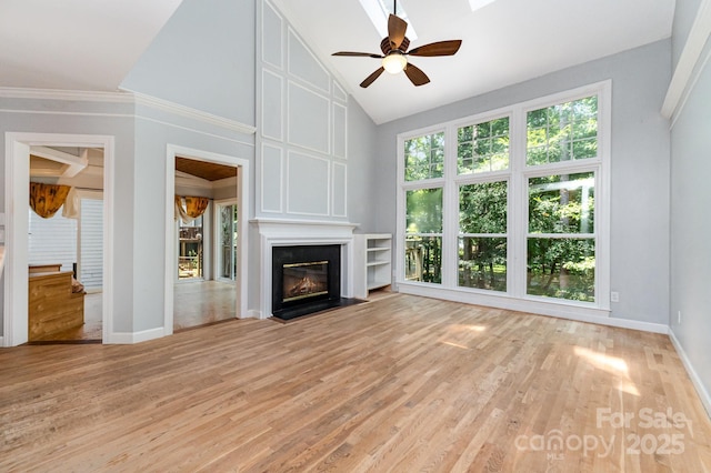 6225 Ash Cove Ln, Charlotte, NC 28269 - unfurnished living room with ceiling fan, light wood-style flooring, a fireplace with flush hearth, high vaulted ceiling, and crown molding