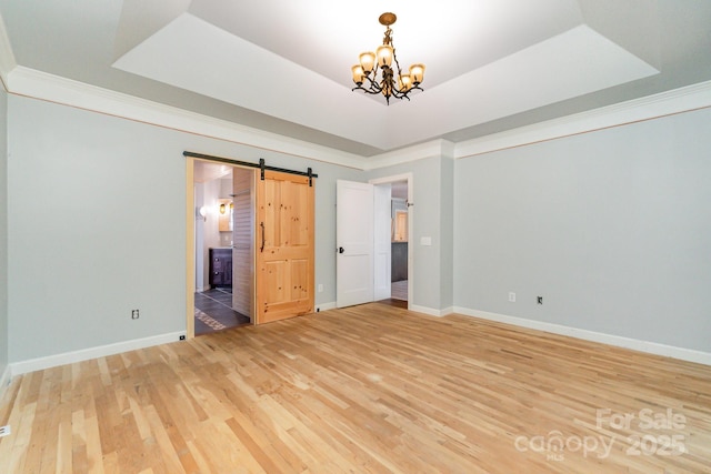 6225 Ash Cove Ln, Charlotte, NC 28269 - spare room featuring a barn door, a chandelier, light wood-style floors, a raised ceiling, and crown molding