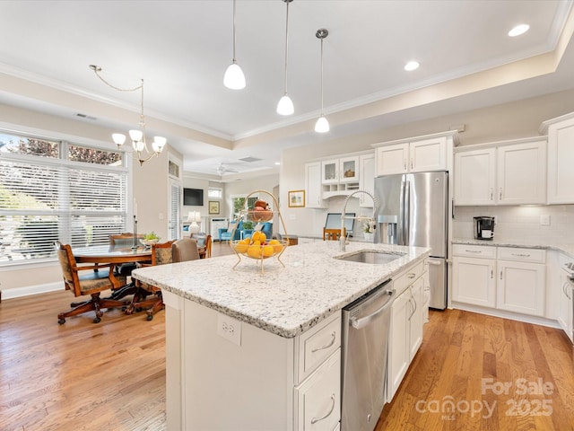 1313 Haywood Park Dr Unit 11, Waxhaw, NC 28173 - kitchen featuring a raised ceiling, ornamental molding, light wood-style flooring, stainless steel appliances, and an island with sink