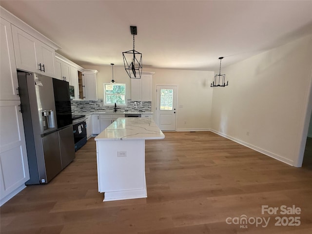 613 3rd Street Pl SW, Conover, NC 28613 - kitchen with stainless steel appliances, tasteful backsplash, wood finished floors, white cabinets, and a kitchen island