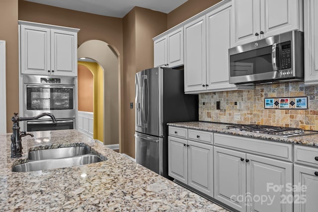 113 Chaska Loop, Troutman, NC 28166 - kitchen featuring stainless steel appliances, white cabinets, arched walkways, and decorative backsplash