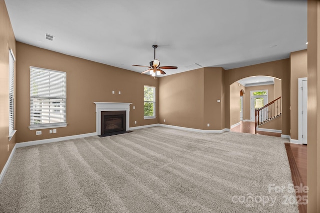 113 Chaska Loop, Troutman, NC 28166 - unfurnished living room with a ceiling fan, arched walkways, carpet flooring, and a fireplace with flush hearth