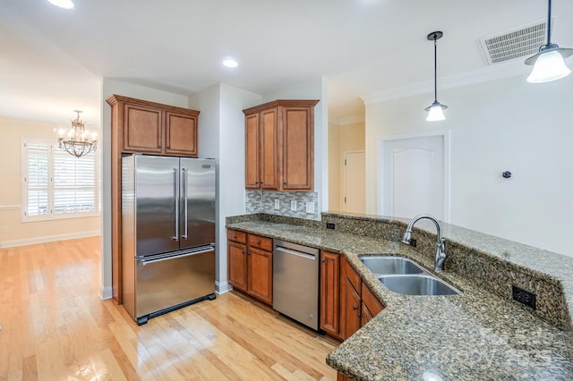 19421 Beaufain St, Cornelius, NC 28031 - kitchen featuring appliances with stainless steel finishes, brown cabinetry, crown molding, light wood-style floors, and a chandelier