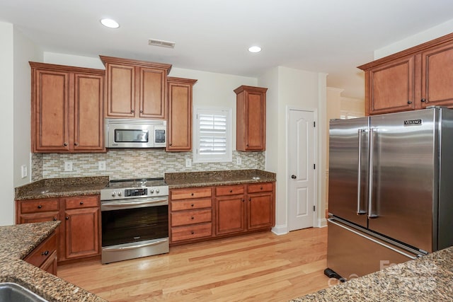 19421 Beaufain St, Cornelius, NC 28031 - kitchen featuring appliances with stainless steel finishes, light wood finished floors, brown cabinetry, tasteful backsplash, and recessed lighting