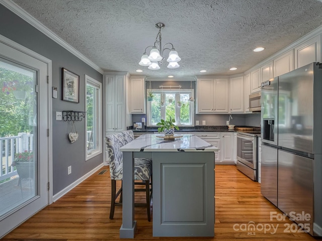 7376 NC-181 Hwy, Morganton, NC 28655 - kitchen with stainless steel appliances, a chandelier, ornamental molding, white cabinetry, and light wood-type flooring