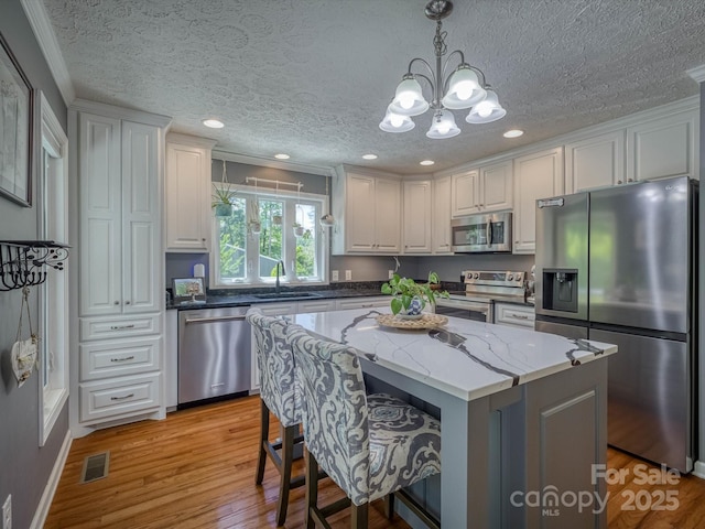 7376 NC-181 Hwy, Morganton, NC 28655 - kitchen featuring stainless steel appliances, white cabinets, a chandelier, a textured ceiling, and crown molding
